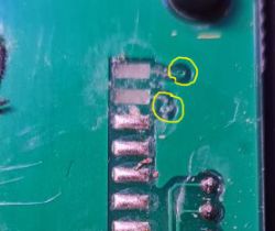 Close-up of a circuit board with broken pins highlighted in yellow.