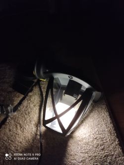 Lampa solarna leży na dywanie, świecąc białym światłem.