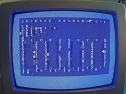 Monitor kineskopowy wyświetlający nieczytelne, zniekształcone dane i tekst na niebieskim tle, prawdopodobnie z komputera retro.