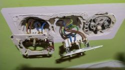 Otwarte gniazdka elektryczne z widocznym chaotycznym okablowaniem trójżyłowym