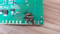 Zbliżenie płytki PCB z przypalonym obszarem i nadtopionymi ścieżkami przy dolnej krawędzi