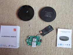 Components of AI universal remote with Wi-Fi IR+RF, including manual, electronics, and box.