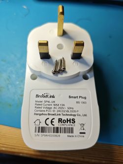 BroadLink smart plug with three brass pins and four screws on a blue surface