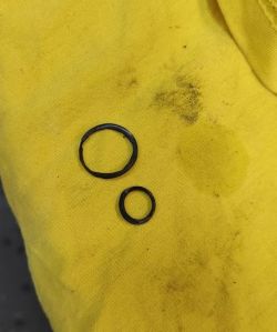 Dwie zużyte uszczelki leżące na żółtym materiale.