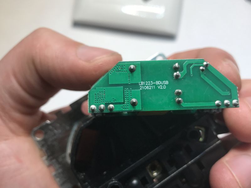 Close-up of a green PCB labeled “LB1223-BDUSB,” held between fingers
