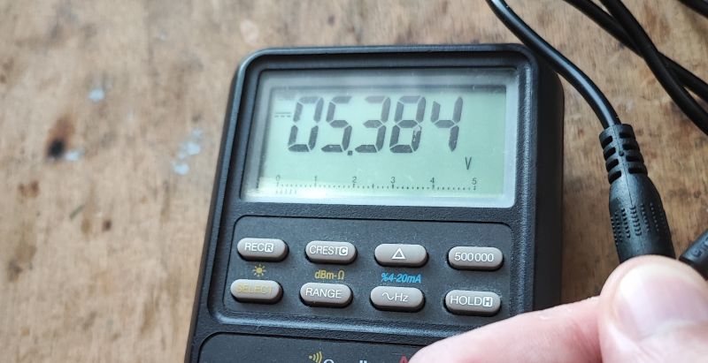 Odczyt na mierniku cyfrowym pokazujący napięcie 5,384 V.