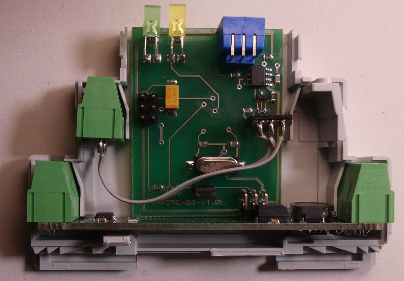 Płytka drukowana z podzespołami elektronicznymi zamontowana w plastikowej obudowie, z zielonymi i niebieskim złączami.