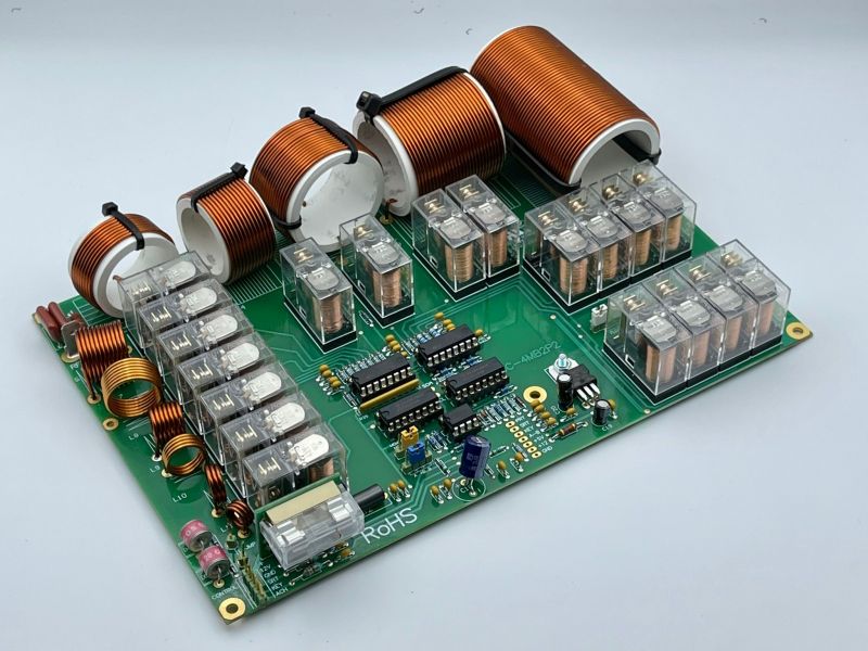 Płyta drukowana JC-4S z komponentami elektronicznymi i cewkami z miedzianego drutu.