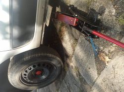 Hydrauliczny podnośnik samochodowy podnosi bok samochodu.