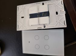 Touch panel with a white casing and four buttons for wall mounting, showing interior electronics.