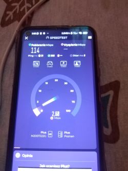 Telefon pokazujący wyniki testu prędkości internetu: 114 Mb/s pobierania, 2,68 Mb/s wysyłania.