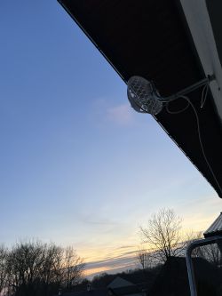 Antena zamontowana na ścianie budynku z widokiem na zachmurzone niebo.