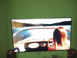 Telewizor wyświetla obraz kobiety prowadzącej łódź na jeziorze.