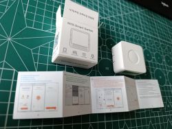 Mini Smart Switch with box and instruction manual on a green cutting mat