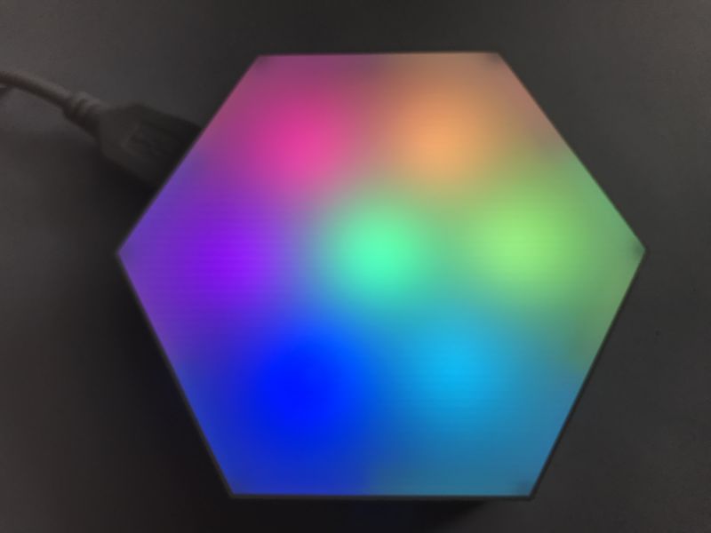 Glowing hexagon LED panel with multicolor gradient, cable connected on the left