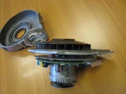 Rozebrany wentylator: silnik z płytką PCB i plastikowym wirnikiem na blacie, obok obudowa