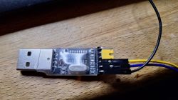 USB to TTL adapter with connected wires on a wooden surface.