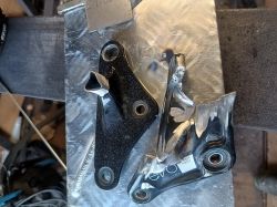Dwa aluminiowe elementy, jeden pęknięty, drugi przypalony, leżą na blasze.