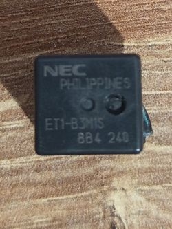 Przekaźnik NEC ET1-B3M1S z oznaczeniem 8B4 24V na drewnianym tle
