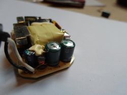 Wnętrze zasilacza z widocznymi kondensatorami i przewodami.