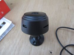 Black Security Camera on Table A black security camera on a stand, placed on a wooden surface.