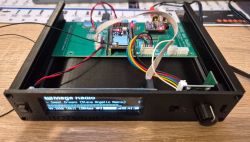 Prototype electronic device with an open case displaying mounted PCB, display, and connectors.