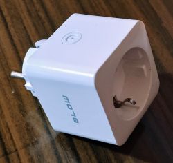 White smart socket from the BLOW brand on a wooden surface, with visible minor damage on the casing.