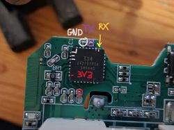 Close-up of a chip on a PCB with labeled GND, TX, RX, and 3V3 pins