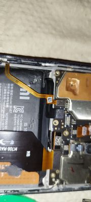 Wnętrze rozebranego smartfona Xiaomi z widocznymi elementami elektronicznymi.