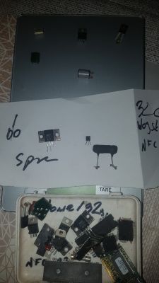 Różne tranzystory i kondensatory wojskowe na tacy i kartce papieru z zapisanymi notatkami.