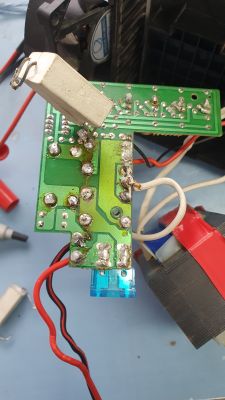 Obwód elektroniczny z podniesionymi ceramicznymi rezystorami, widoczne ścieżki i elementy lutowane na zielonej płytce.