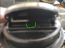 Zbliżenie na mechanizm klamki bagażnika z widocznym zaczepem zaznaczonym na zielono.