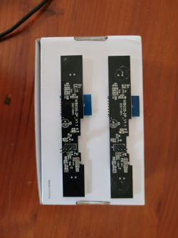 Two black PCBs lying on a white background, differing only in the amount of adhesive traces.