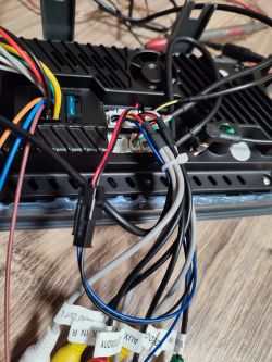 Widok na tylną część urządzenia elektronicznego z licznymi przewodami o różnych kolorach. Przewody czerwony i czarny wychodzą z wentylatora, a niebieski i czarny z kostki AV.