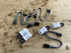 Four DHT22 sensors with cables on a wooden surface