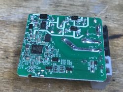 Inside the Sonoff Mini R2 Module with ESP8285 Chip Sonoff Mini R2 module's electronic board with ESP8285 chip on a wooden background.
