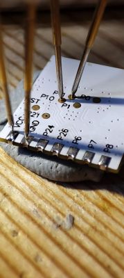 Close-up of the BK7231N electronic module with connected test probes.