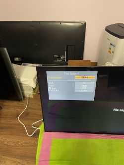Telewizor z wyświetlonym menu na ekranie i tyłem innego telewizora w tle.