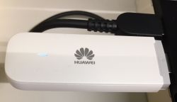 Biały modem USB Huawei z niebieską diodą, podłączony do portu USB.