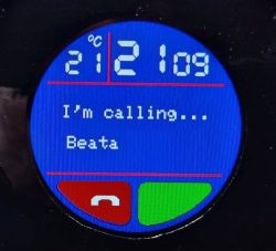 Okrągły wyświetlacz pokazuje 21:09, 21°C i ekran dzwonienia do „Beata” z czerwonym i zielonym przyciskiem