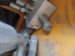 Aluminiowy blok hydrauliczny z przewodami i złączami na żółtej ramie maszyny