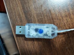 Złącze USB z wbudowanym programatorem i włącznikiem na drewnianym blacie.