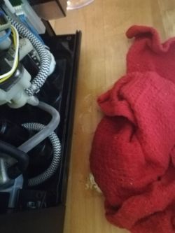 Otwarte wnętrze ekspresu do kawy z przewodami i czerwoną ściereczką na blacie.