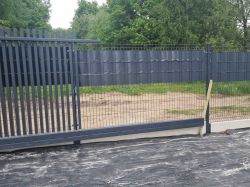 Brama przesuwna z metalową konstrukcją znajduje się blisko słupka i ogrodzenia, pozostawiając bardzo mało miejsca po bokach.