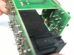 Zbliżenie na płytkę drukowaną z elektroniką oraz elementami lutowanymi i plastikowym złączem.