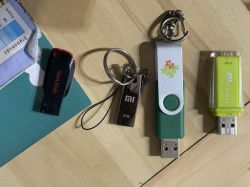 Cztery różne pendrive'y leżące na drewnianym blacie.