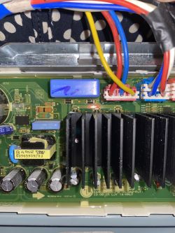 Zbliżenie na układ elektroniczny z kolorowymi przewodami, kondensatorami i radiatorem.
