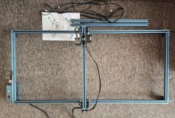 Zestaw rozszerzonej maszyny Sculpfun S9 z ramą roboczą i przewodami na dywanie.