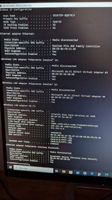Zrzut ekranu z wynikami polecenia ipconfig/all w systemie Windows pokazujący różne adaptery sieciowe.