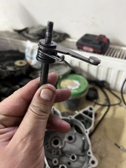 Dłoń trzymająca metalowy element mechaniczny na tle warsztatu.